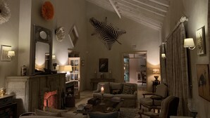 A cozy living room with a fireplace, plush sofas, a zebra head sculpture, and a well-lit ambiance.