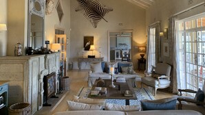 A spacious living room with a fireplace, comfortable seating, and a large zebra mural on the wall.