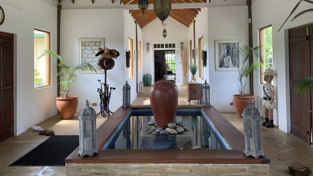 A spacious room with a wooden ceiling, a central pool, and potted plants.