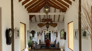 A hallway with a stone floor, wooden beams, and a central decorative fountain.