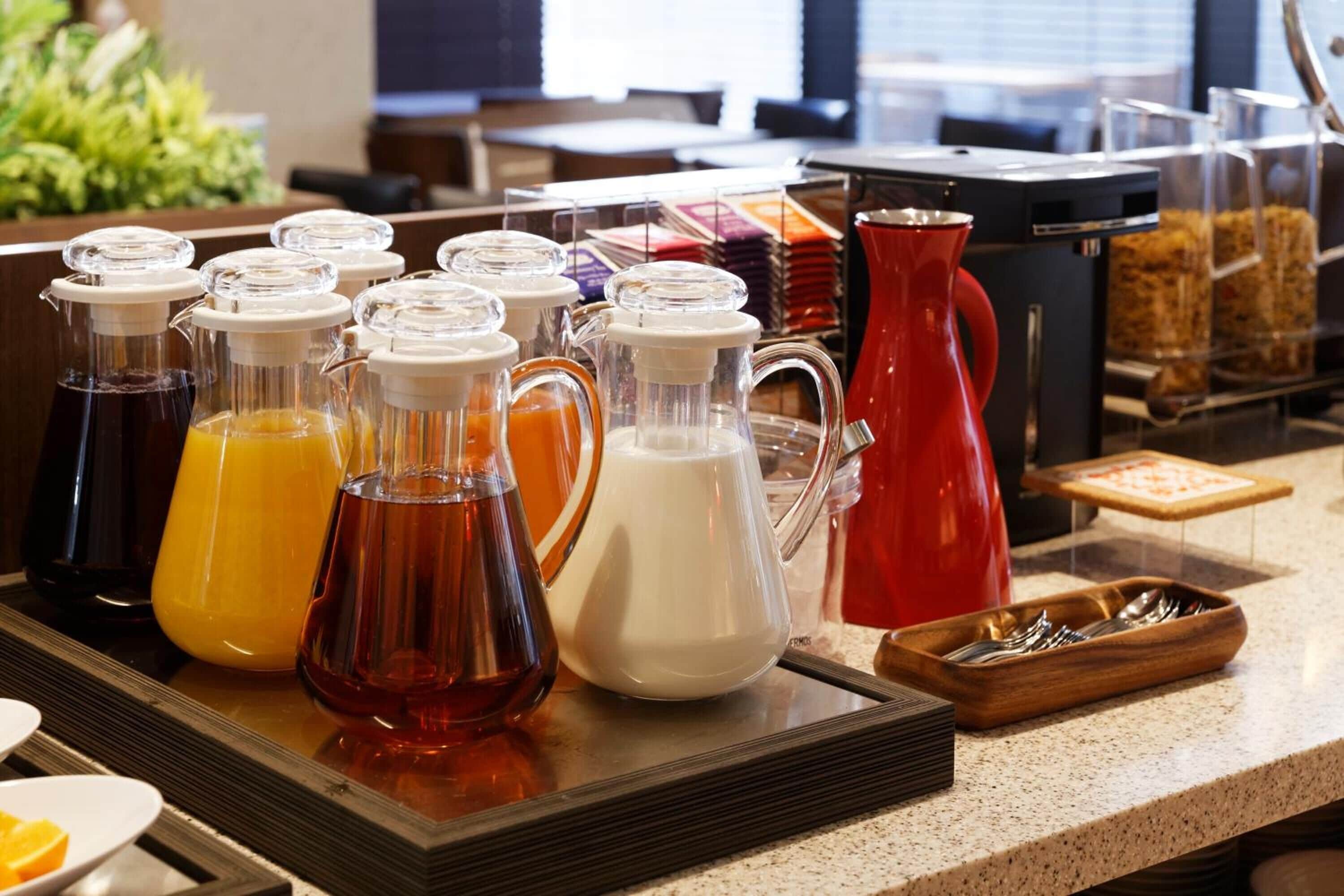 A buffet setup with various beverage dispensers and a coffee maker.