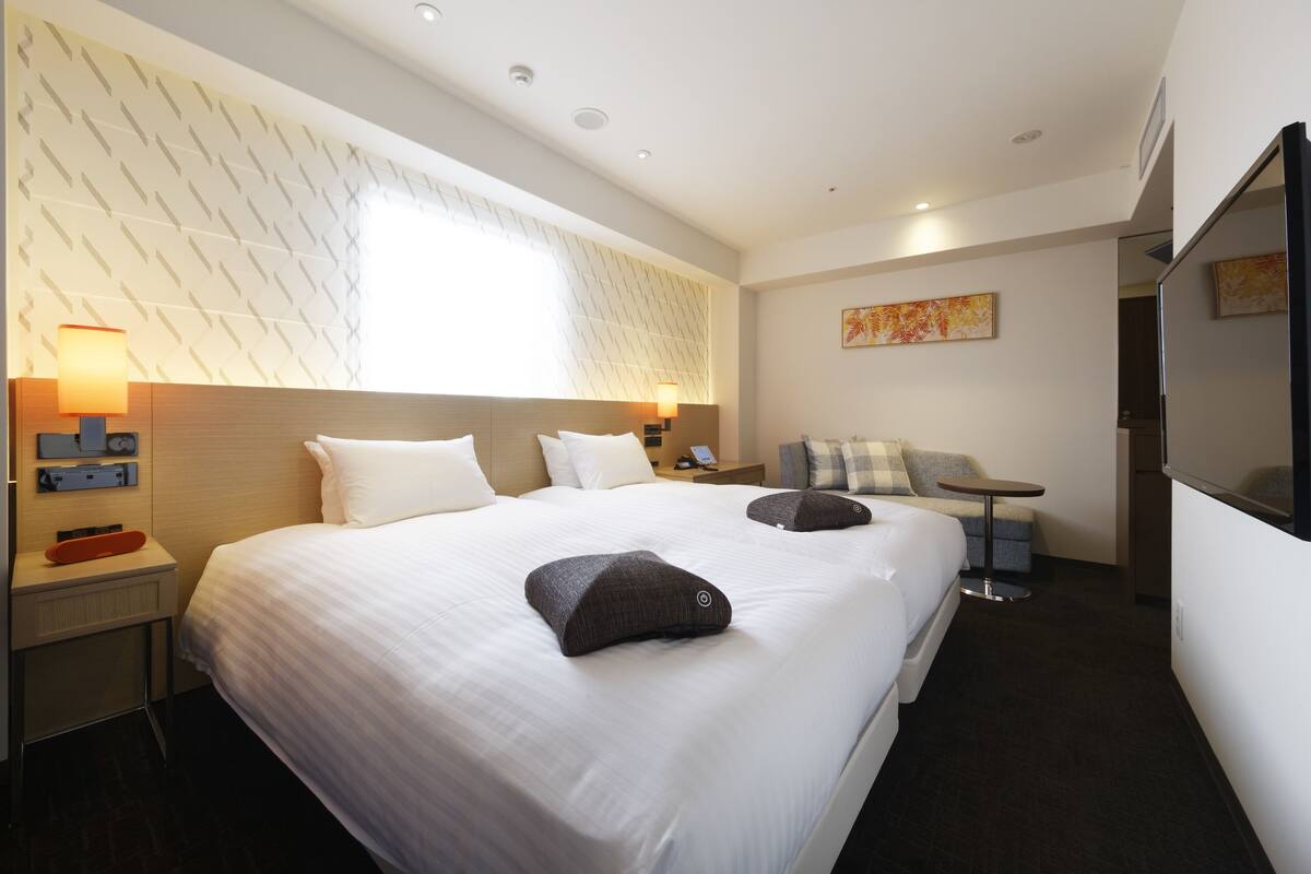 Ein Hotelzimmer mit einem großen Bett, Nachttischen, einem Schreibtisch und einem Fernseher.