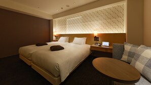 Une chambre d’hôtel avec un grand lit, une table de chevet avec une lampe, une petite table ronde et un canapé.