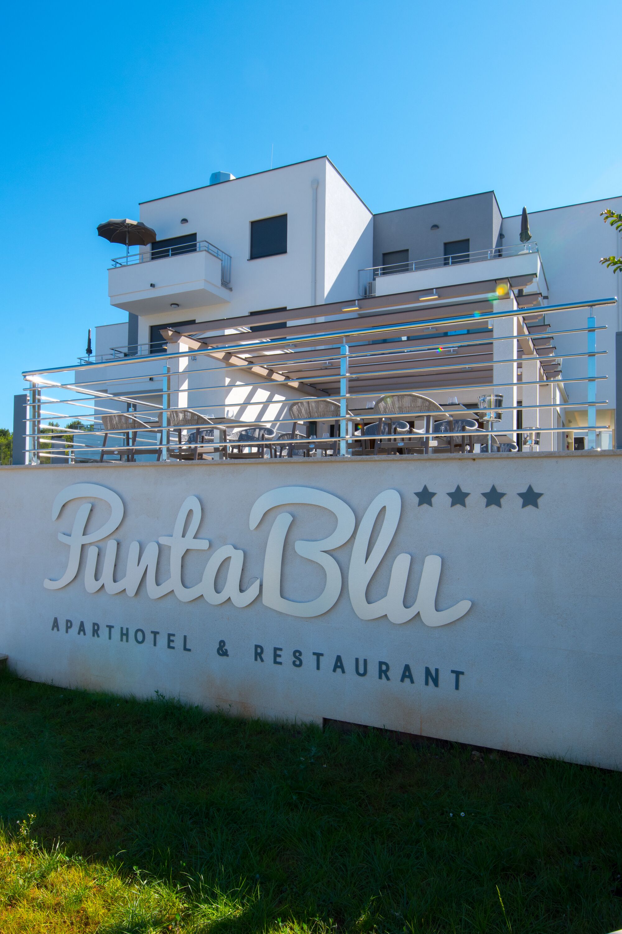 A modern building with a sign that reads "PuntaBlu" and "APARTHOTEL & RESTAURANT".