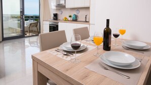 Un comedor con una mesa dispuesta para dos personas, con copas de vino, una botella de vino y un vaso de jugo de naranja.