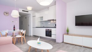 A modern living room with a white table, pink sofa, and a TV mounted on the wall. - Apartments Dva Galeba (Bol)