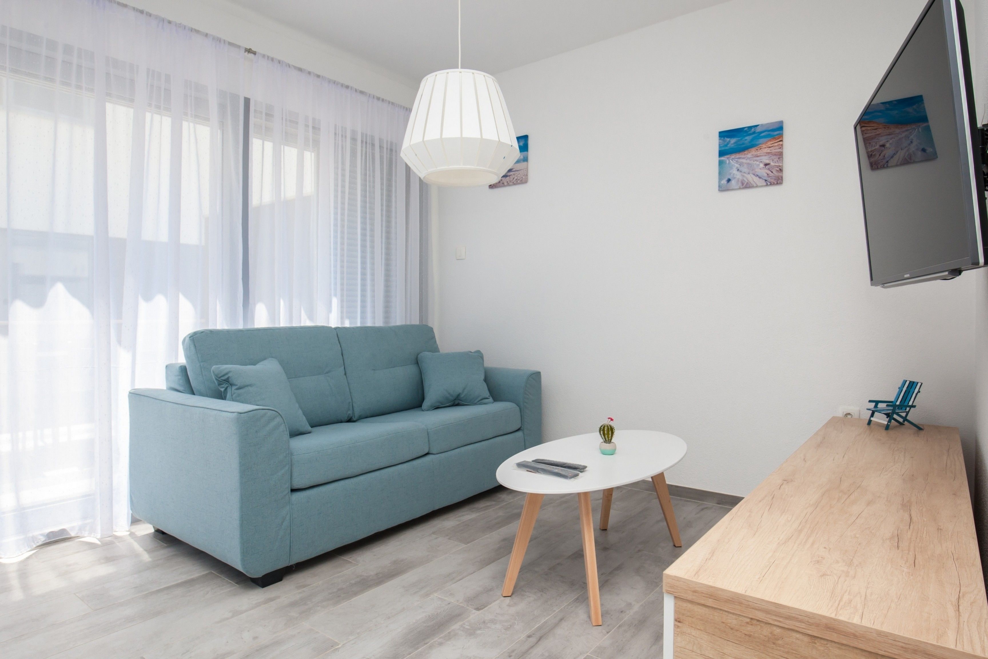 A modern living room with a light blue sofa, a white coffee table, and a wooden side table.