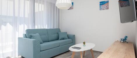 A modern living room with a light blue sofa, a white coffee table, and a wooden side table.