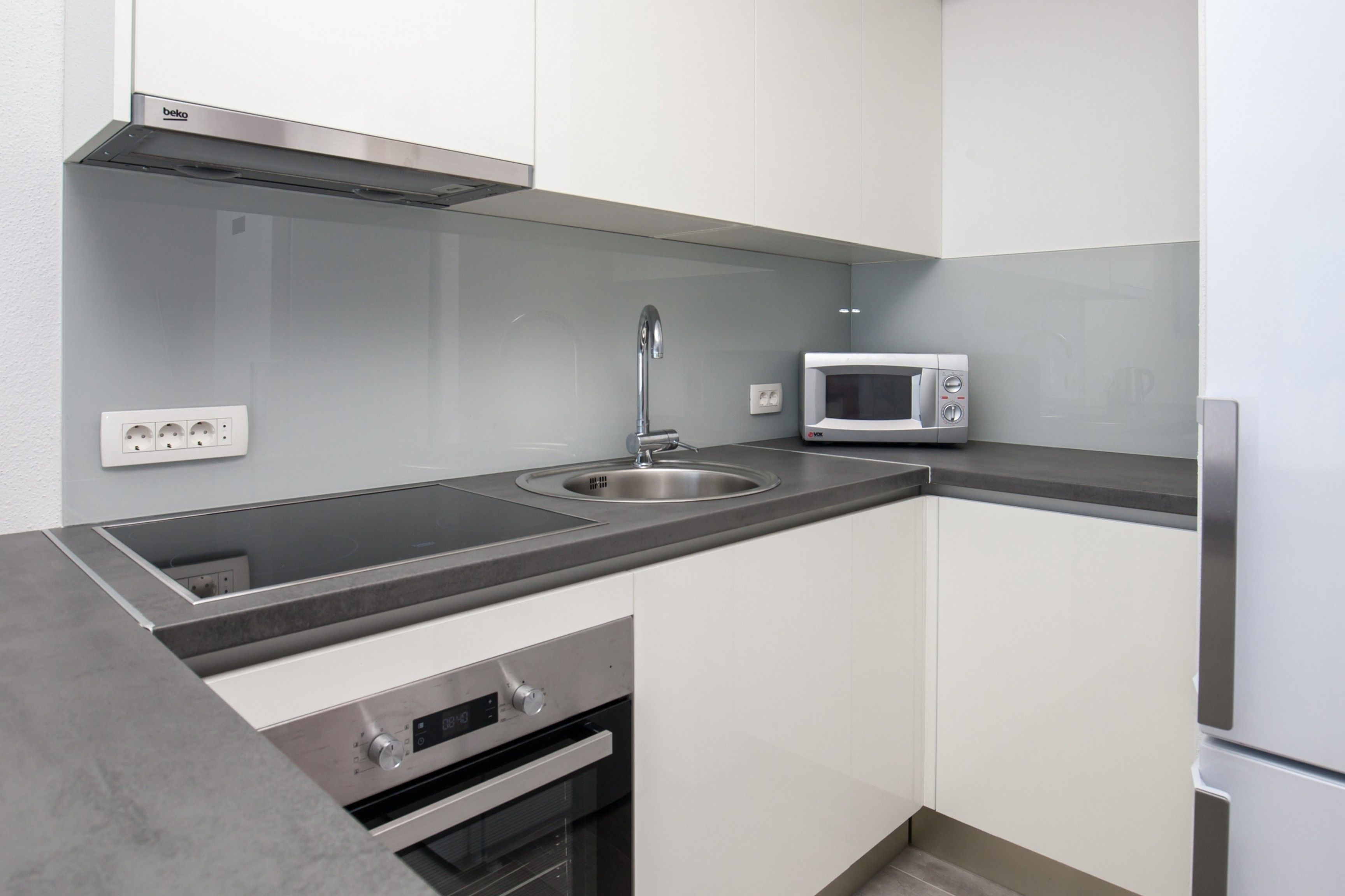 A modern kitchen with a stainless steel sink, a microwave, and a built-in oven.