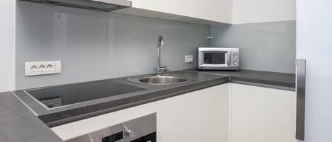 A modern kitchen with a stainless steel sink, a microwave, and a built-in oven.