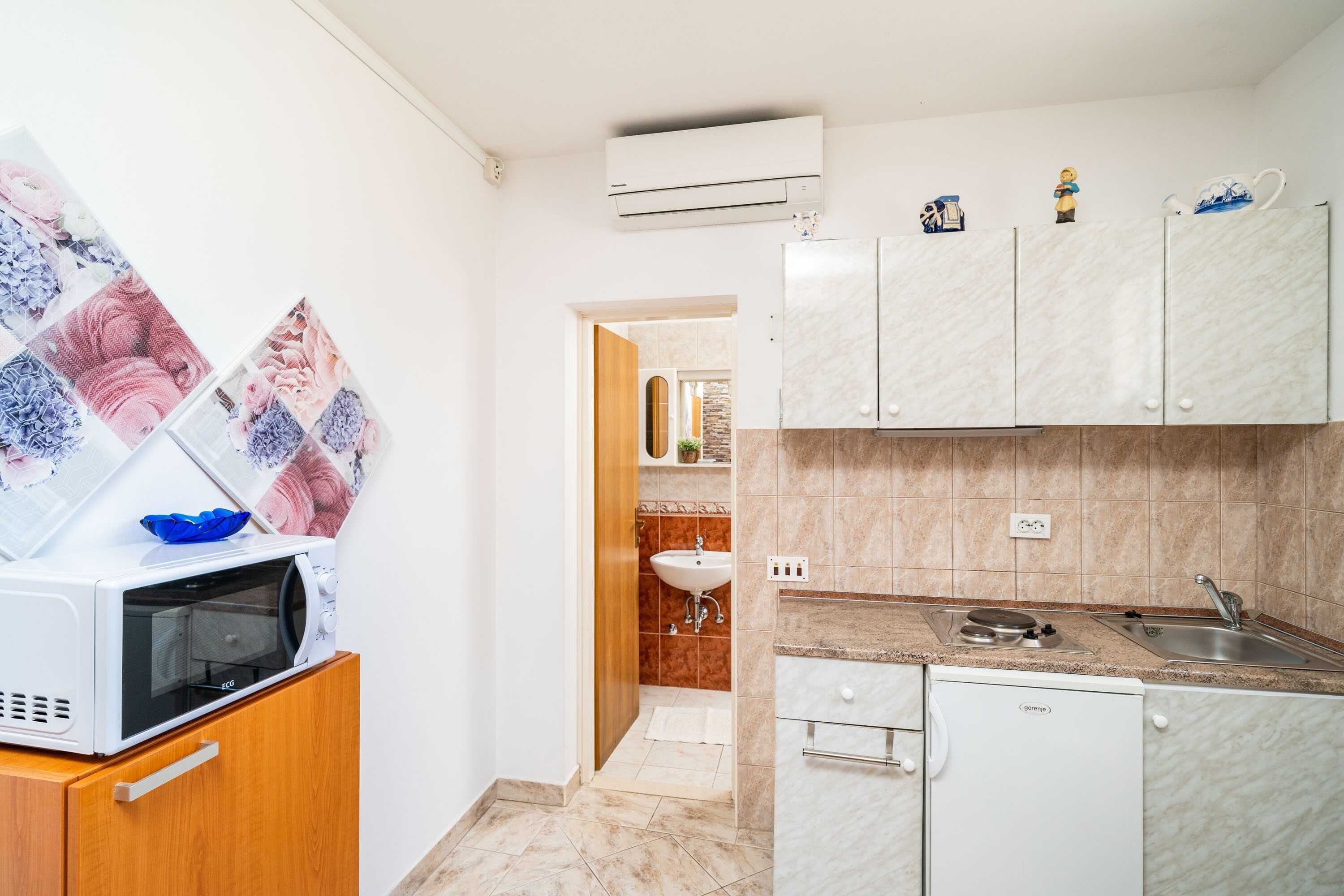 Cocina compacta equipada con microondas, refrigerador pequeño y lavamanos.