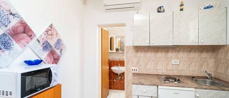 Cocina compacta equipada con microondas, refrigerador pequeño y lavamanos.