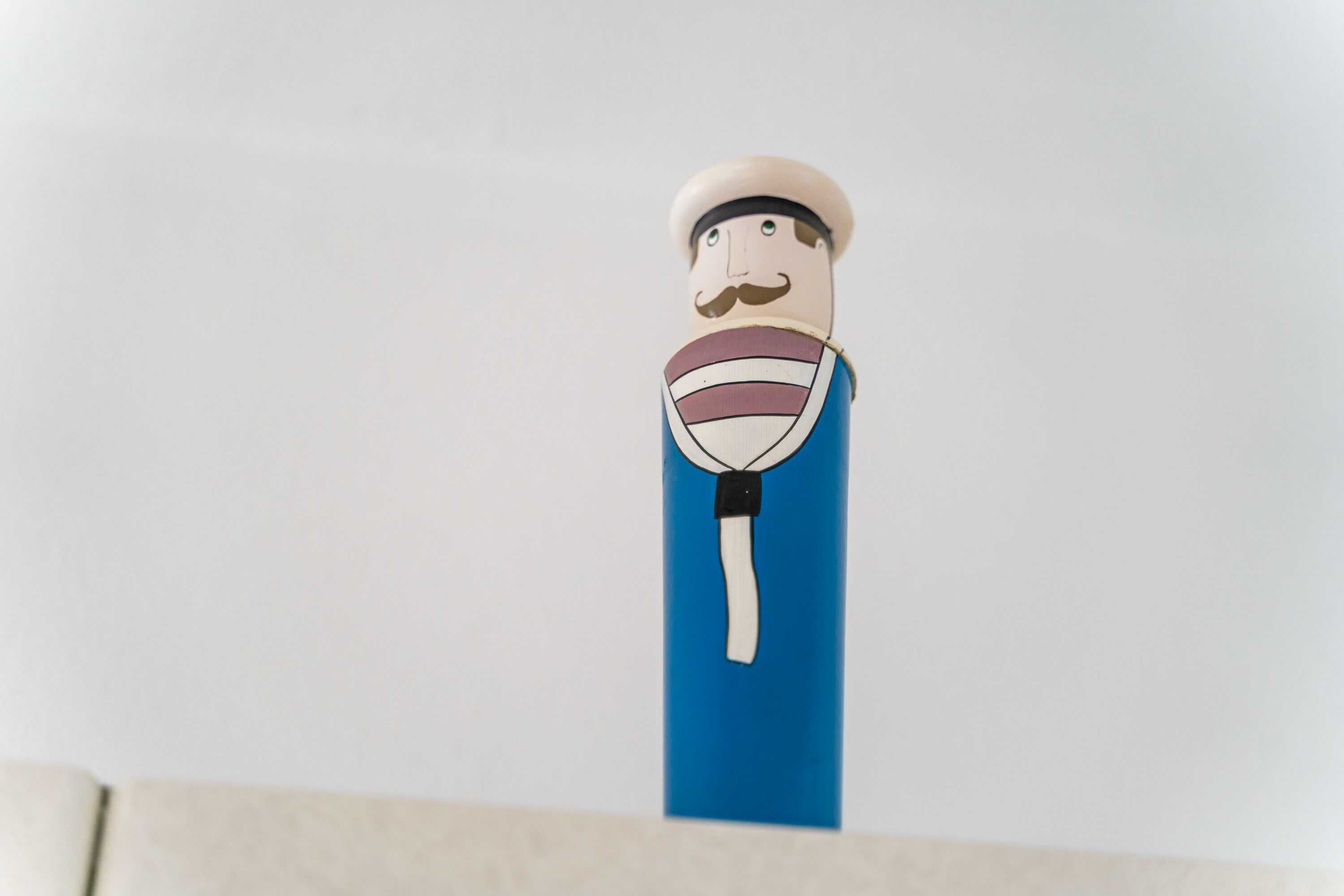 Un objet vertical surmonté d’une figurine, qui pourrait être un élément décoratif ou une partie d’un meuble.