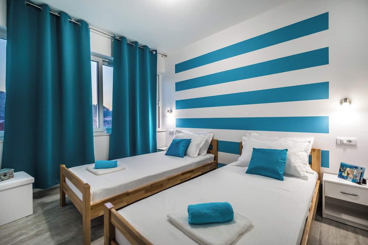 Ein Hotelzimmer mit zwei Betten, einem Fenster und Blick auf die Stadt.