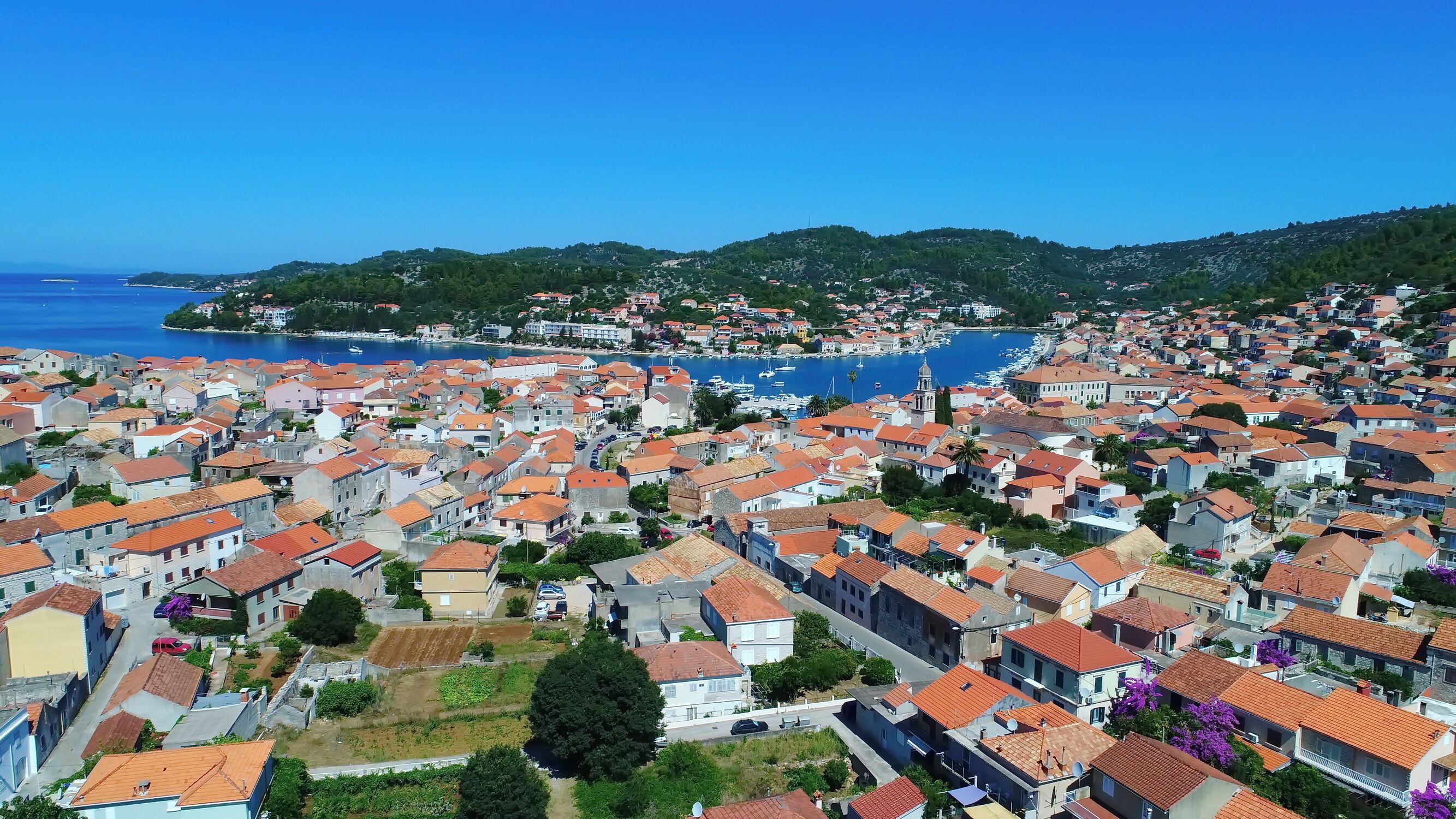 A coastal town with tightly packed buildings, a marina, and a prominent church tower.