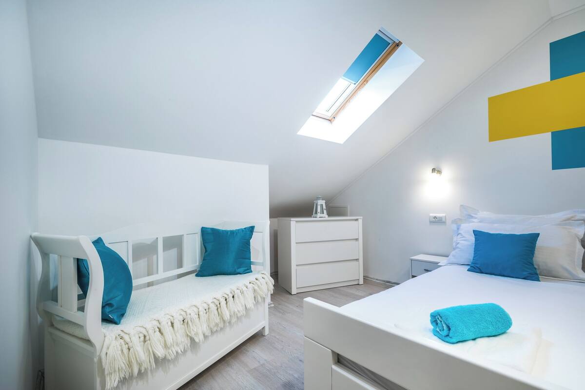 Ein Schlafzimmer mit zwei Betten, einem Oberlicht, einer weißen Kommode und einem Nachttisch.