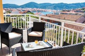 A balcony with wicker furniture, a table, and two glasses of orange juice.