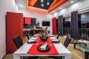 A modern dining area with a red tablecloth, black plates, and a central bowl with flowers.
