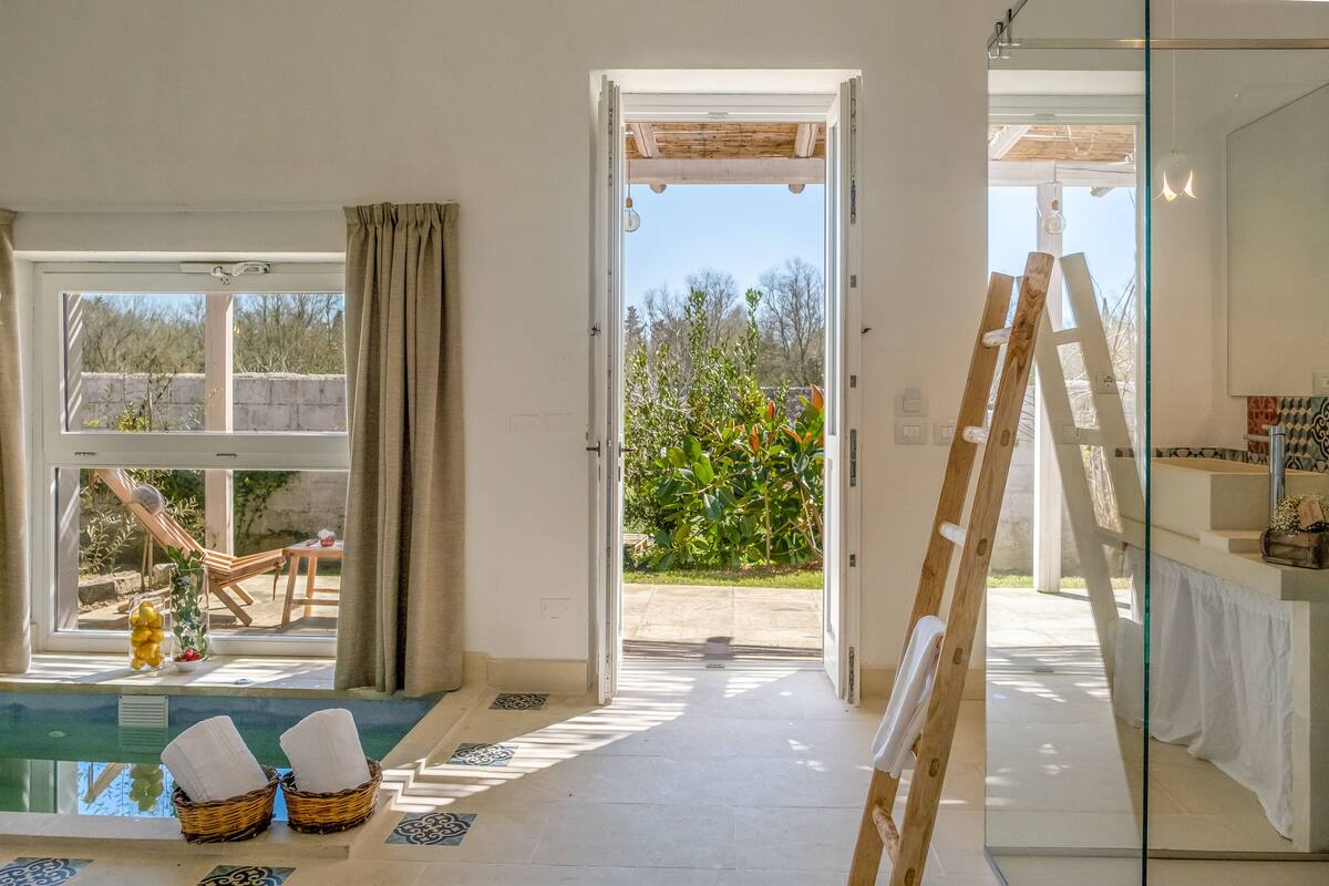 Ein modernes Zimmer mit Glastür zu einem Außenbereich, einem Pool und einer Holzleiter.