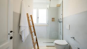 Un baño moderno con cabina de ducha de vidrio, inodoro y lavamanos.