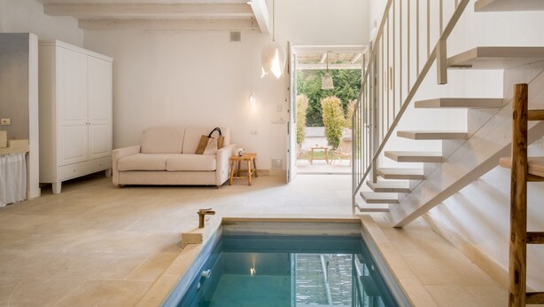 A spacious living area with a built-in pool, a staircase, and a view of the outdoors. - Masseria Rauccio (Melendugno)