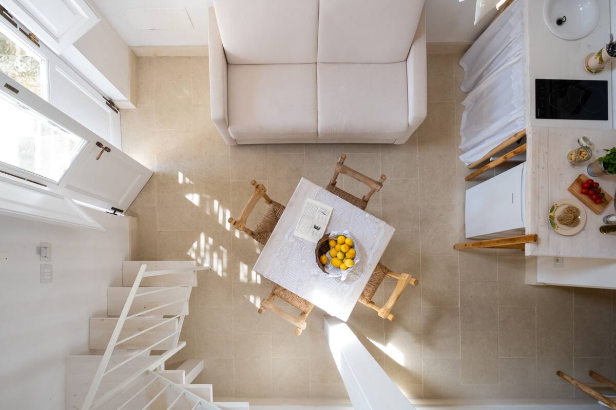 Eine moderne Küche mit Essbereich, ausgestattet mit einem weißen Sofa, einem Tisch mit einer Zitronenschale und einem Holzstuhl.