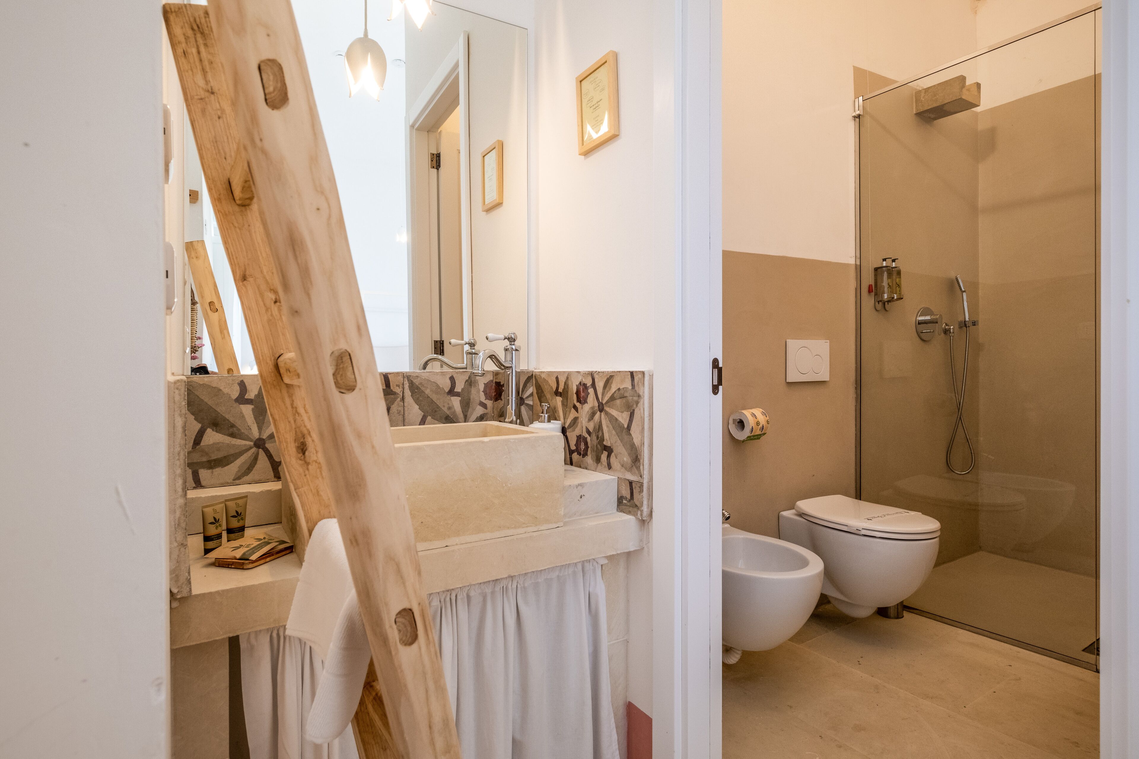 A modern bathroom with a wooden vanity, a large mirror, a shower, and a bidet.