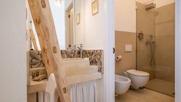 A modern bathroom with a wooden vanity, a large mirror, a shower, and a bidet.