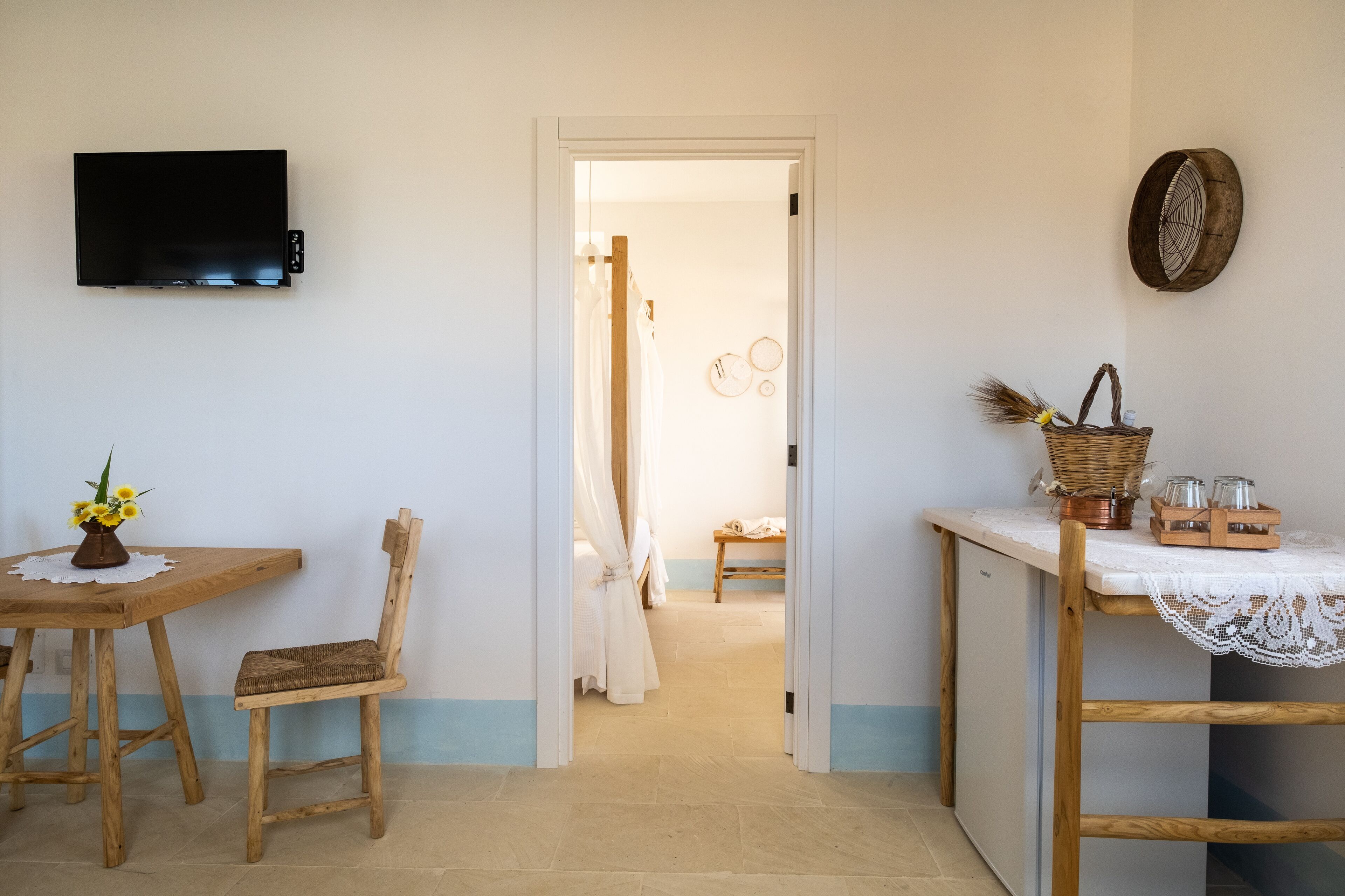 Une pièce avec une table en bois, une chaise, un téléviseur fixé au mur et une porte donnant sur une autre pièce.