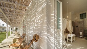 A sunlit room with a wooden bench, a hat, and a small table with towels. - Masseria Rauccio (Melendugno)
