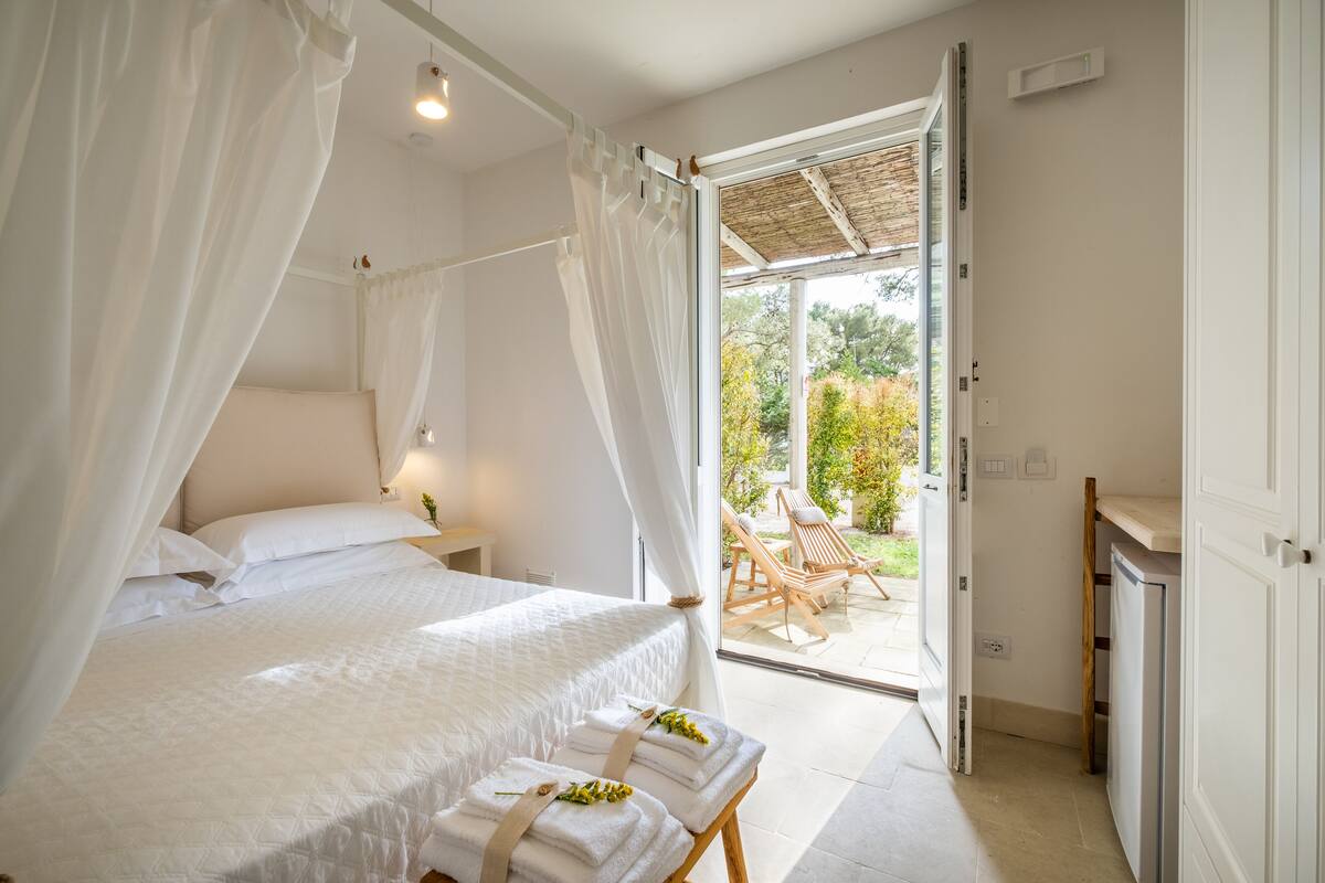 Ein Schlafzimmer mit Bett, Nachttisch und einem Vorhangfenster.