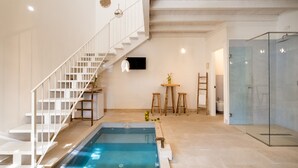 A modern indoor pool area with a glass-enclosed shower, a white staircase, and a minimalist design. - Masseria Rauccio (Melendugno)