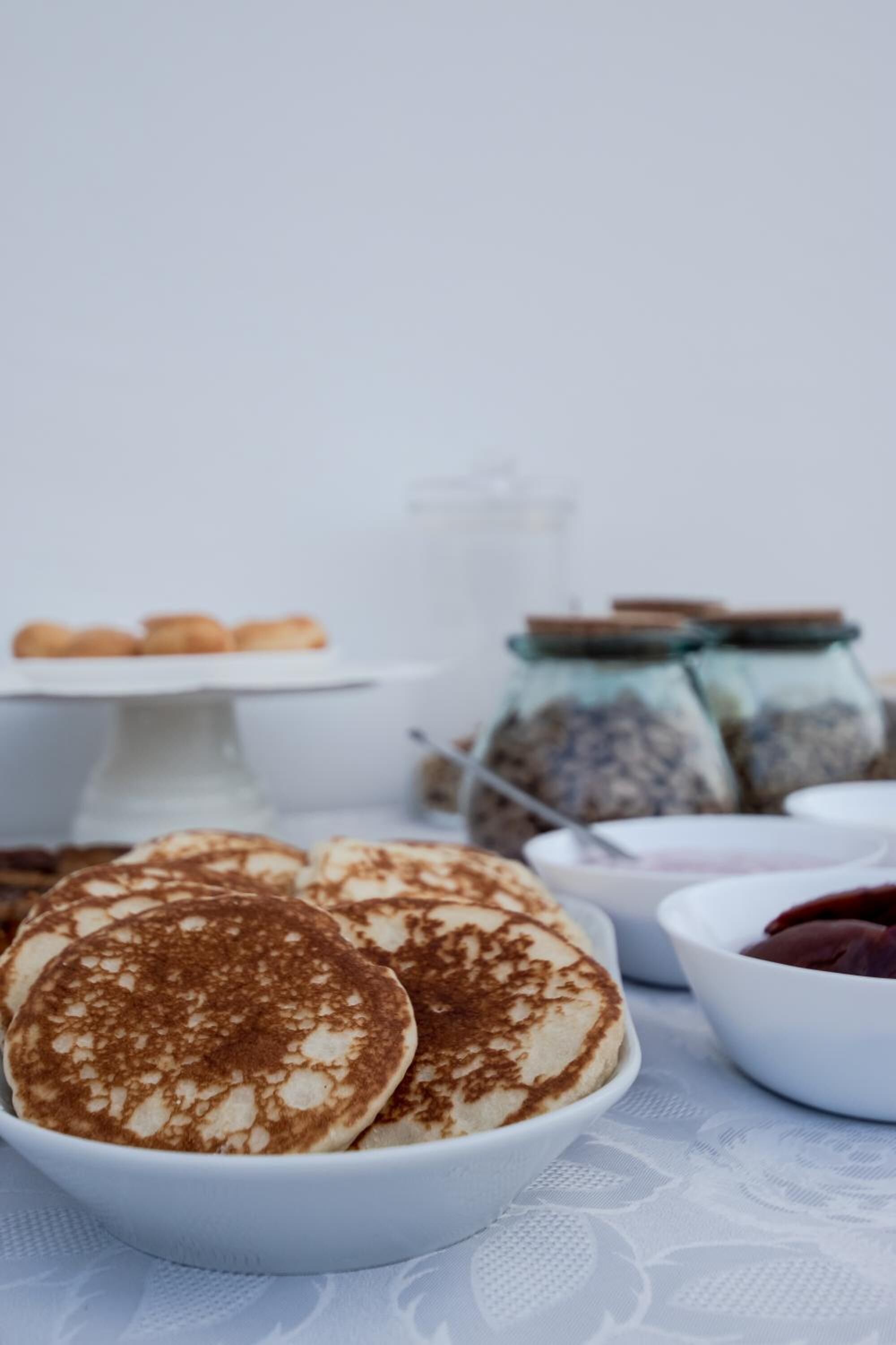 A bowl of pancakes with a white tablecloth.