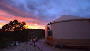 A single-story yurt with a large window, situated on a gravel path with a table and chairs nearby. - Yurt Overlook #10 with AC and Private Bath 2 Kings (Orderville)