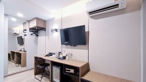 Habitació d'hotel moderna amb escriptori, cadira i televisió de pantalla plana penjada a la paret.
