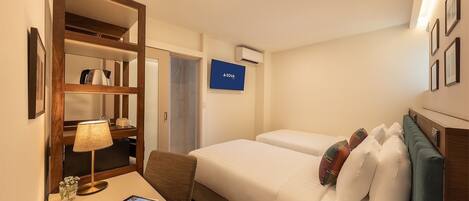 Una habitación de hotel con cama, escritorio con lámpara, televisión y minibar.