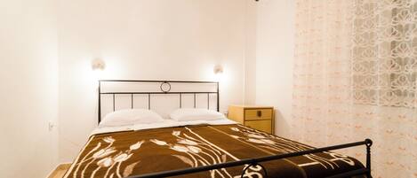 A single bed with a headboard, a bedside table, and a wall-mounted air conditioner.