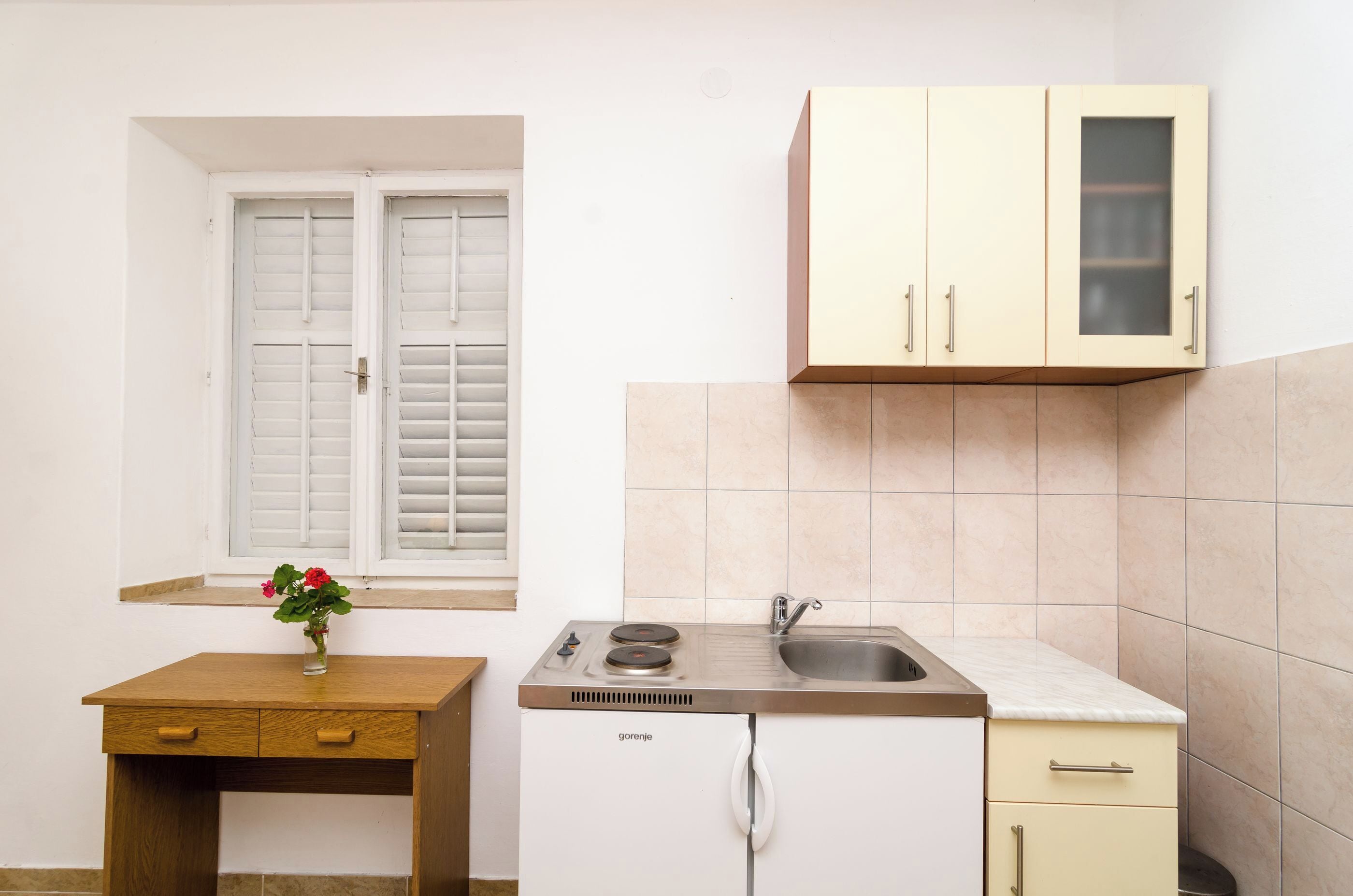 Una cocina compacta con ventana, lavamanos y armarios.