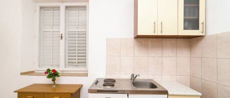 Una cocina compacta con ventana, lavamanos y armarios.