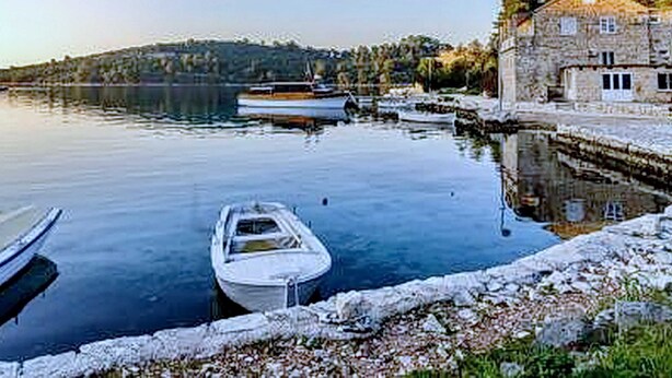 Un lago tranquilo con barcos, un edificio de piedra y una colina al fondo.