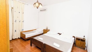Un dormitorio con dos camas, una mesita de noche de madera, una lámpara y un equipo de aire acondicionado.