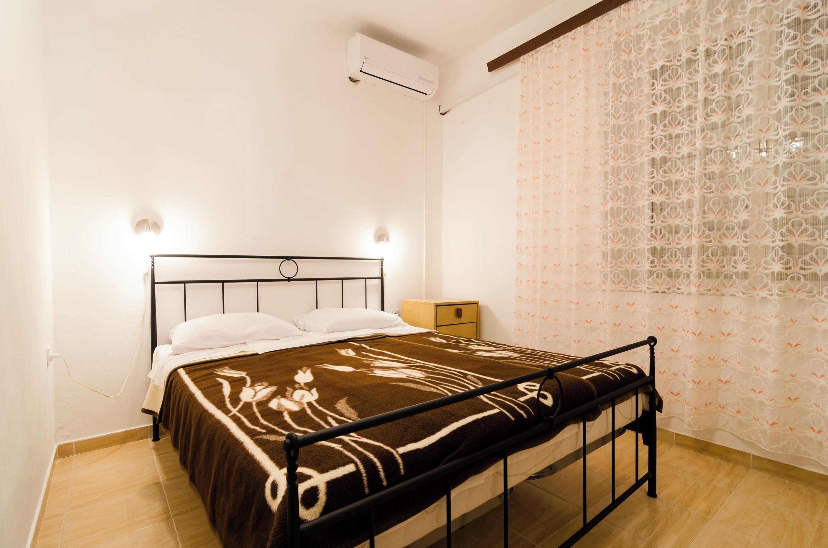 Un dormitorio con cama, mesita de noche y aire acondicionado.