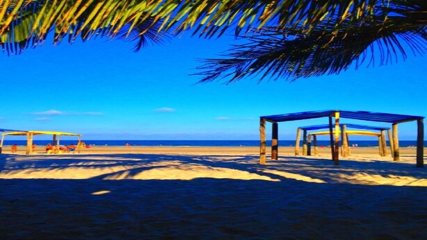 A beach with wooden structures and a clear blue sky.