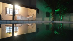 A room with a large window, a bed, and a view of a pool.