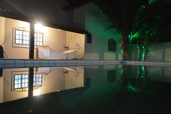 A room with a large window, a bed, and a view of a pool.