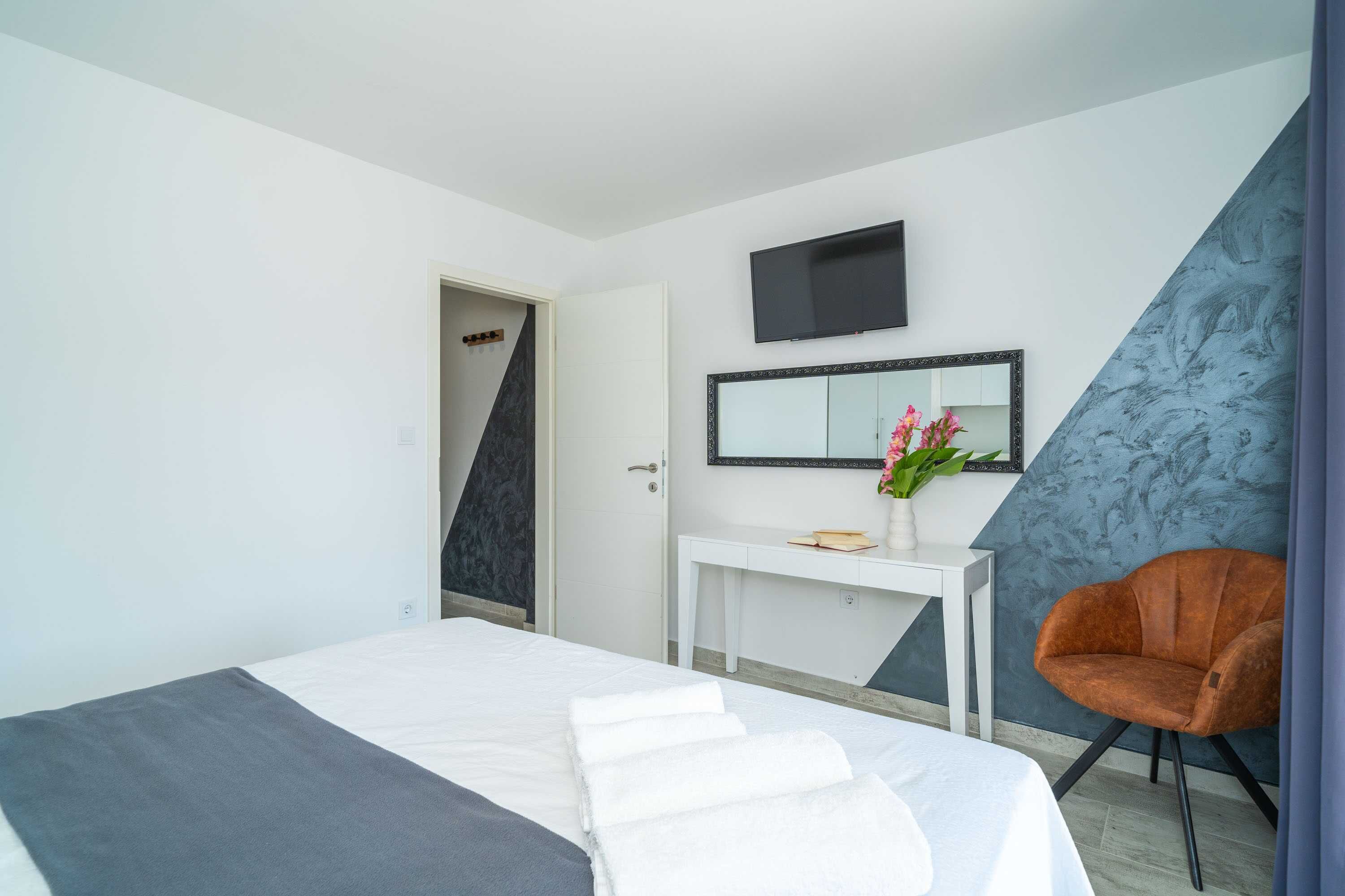 Une chambre d’hôtel avec un lit, un bureau blanc, une chaise, une télévision et un miroir.