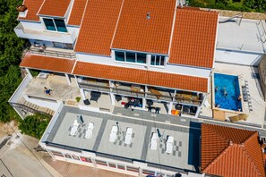 Un immeuble à plusieurs étages doté d’une piscine sur le toit, d’un espace extérieur aménagé pour s’asseoir et d’une terrasse couverte.