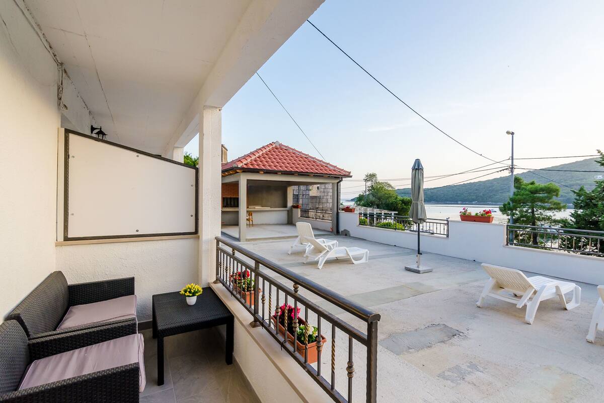 A balcony with a sofa, a table, and potted plants.