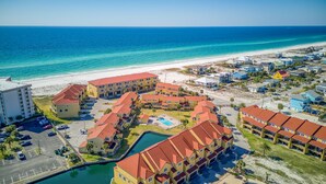 A coastal hotel with multiple buildings, a swimming pool, and a beach view.