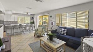 A modern living room with a sofa, coffee table, and a dining area with chairs and a table.